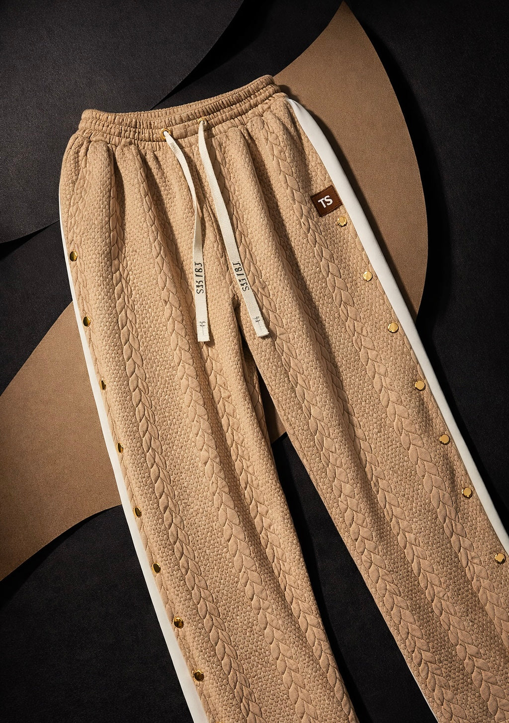 Camel taupe waffle knit pants close-up with textured fabric, drawstring waist, and gold hardware detail